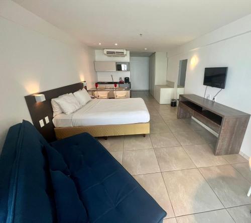 a bedroom with a bed and a couch and a television at Refúgio do Mar 705 - Condomínio Edifício Ritz Suítes Home Service in Maceió