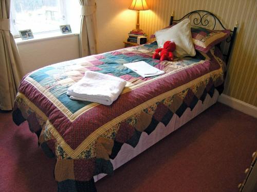 a bedroom with a bed with a teddy bear on it at Achnabobane Farmhouse in Spean Bridge