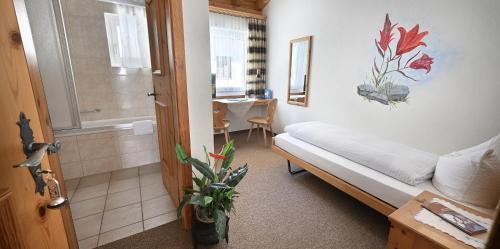 a small room with a bed and a bathroom at Hotel Acla Filli in Zernez