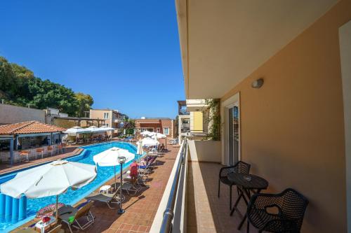 a balcony with a swimming pool and tables and umbrellas at Porto Kalamaki Hotel in Kalamaki Chanion
