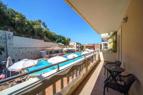 a balcony with a swimming pool with umbrellas and chairs at Porto Kalamaki Hotel in Kalamaki Chanion