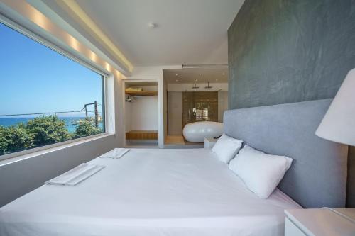 a bedroom with a white bed and a large window at Porto Kalamaki Hotel in Kalamaki Chanion
