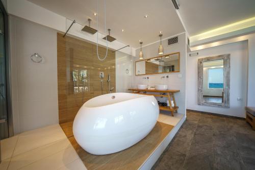 a bathroom with a large white tub and a shower at Porto Kalamaki Hotel in Kalamaki Chanion
