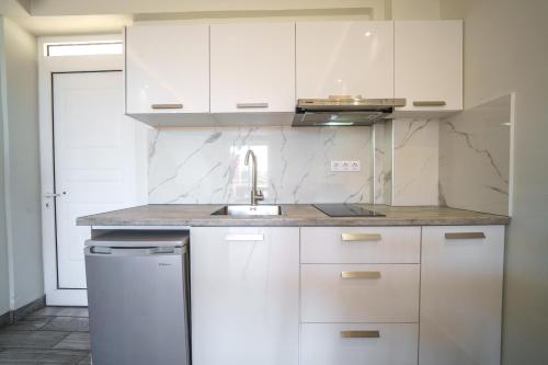 a white kitchen with a sink and white cabinets at Porto Kalamaki Hotel in Kalamaki Chanion