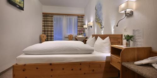 a bedroom with a large bed with white sheets at Hotel Acla Filli in Zernez