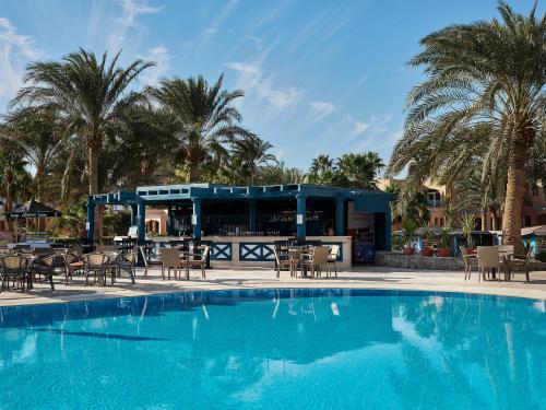 a swimming pool with tables and chairs next to a building at Club Paradisio El Gouna Red Sea in Hurghada