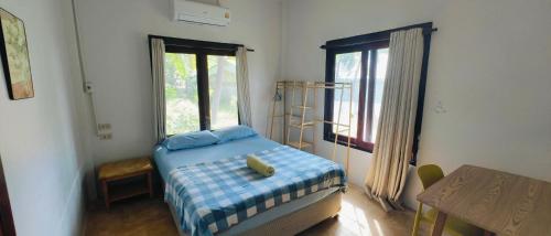 a bedroom with a bed and a table and window at Secret Thai Peace No1 in Thongsala