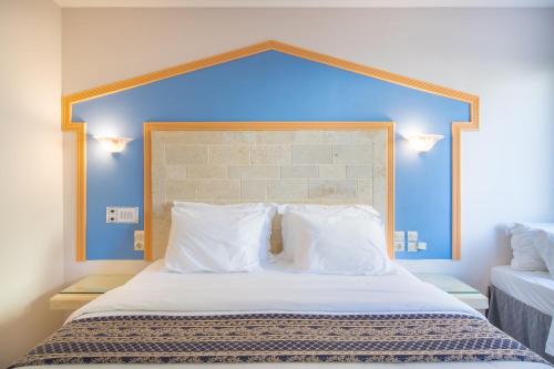 a bedroom with a large bed with a blue headboard at Astoria Hotel in Agia Galini
