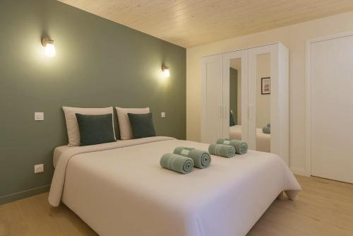 a large white bed with two green pillows on it at L Oasis Mâconnaise d Excellence Conciergerie in Mâcon