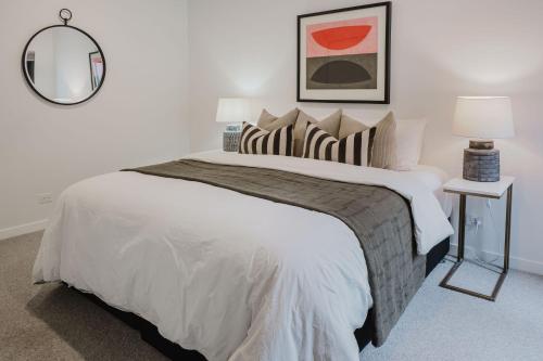 a bedroom with a large white bed with a mirror at Sheppard Art House Townhouse in Bright