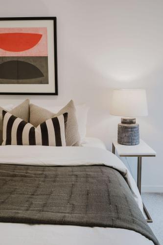 a white bedroom with a bed and a table with a lamp at Sheppard Art House Townhouse in Bright