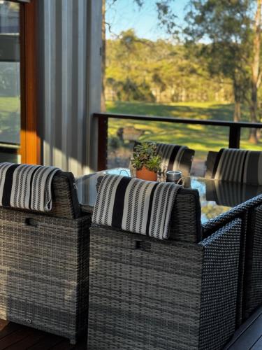 a group of wicker chairs sitting on a balcony at Tuckers Lane Boutique Accommodation in Rothbury