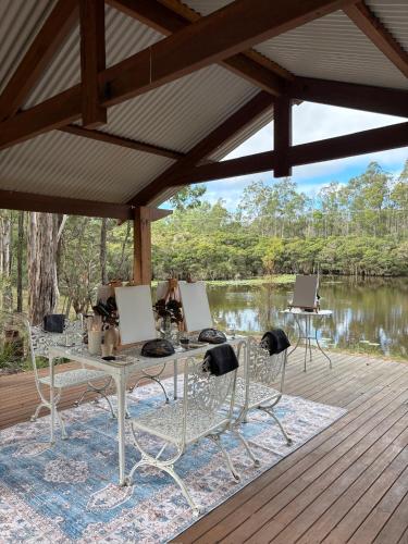 a table and chairs on a deck next to a lake at Tuckers Lane Boutique Accommodation in Rothbury