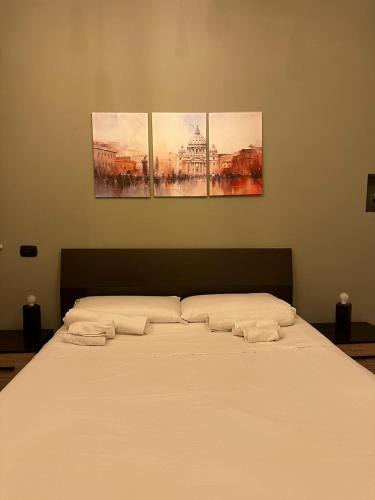 a bed in a room with three paintings on the wall at La Dimora dei Consoli - Apartment San Peter in Rome