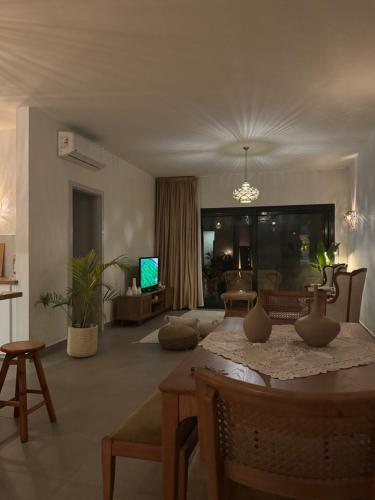 ein Wohnzimmer mit einem Tisch und ein Wohnzimmer mit einem Sofa in der Unterkunft Cozy Garden Flat with Full Kitchen in Madīnat aţ Ţalāʼi‘