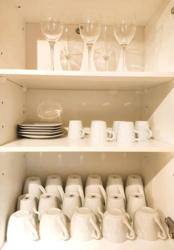 a cupboard filled with white dishes and wine glasses at Top duplex Apartment Zurich-Limmattal in Killwangen