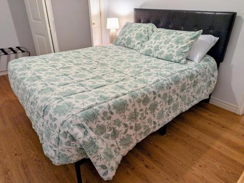 Una cama con una manta verde y blanca. en The Convenient Suite, en Charlottetown