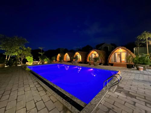 een blauw zwembad voor een huis 's nachts bij Bình An Mountain Side Bungalow in Nguyên Ngoại