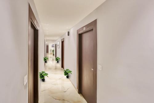 a hallway with two potted plants on the floor at Hotel O Sky Hotel in Rohtak