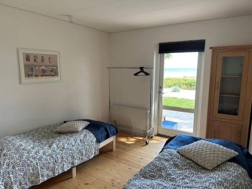 a bedroom with two beds and a door to the ocean at House direct to beach in Greve