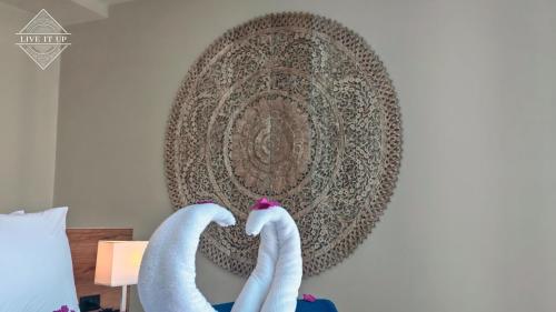 two towel swans on a wall with a painting at Santi Tara Villas in Amphoe Koh Samui