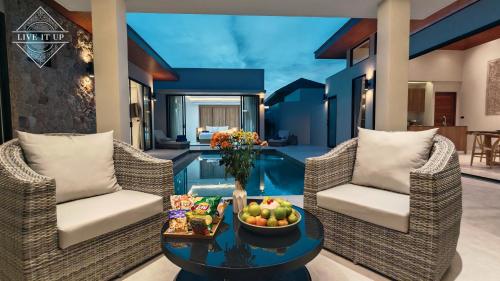 a living room with two chairs and a table with a bowl of fruit at Santi Tara Villas in Amphoe Koh Samui