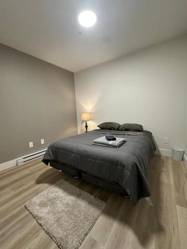 a bedroom with a bed with a black blanket and a rug at Private Room Lakeview House- Westmount in Moncton