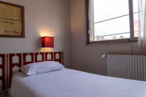 a bedroom with a white bed with a window at Hotel Ours Blanc - Victor Hugo in Toulouse