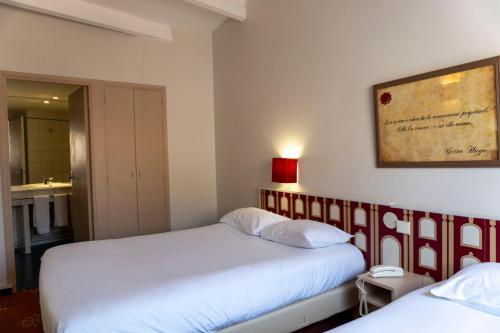 a bedroom with two beds and a picture on the wall at Hotel Ours Blanc - Victor Hugo in Toulouse