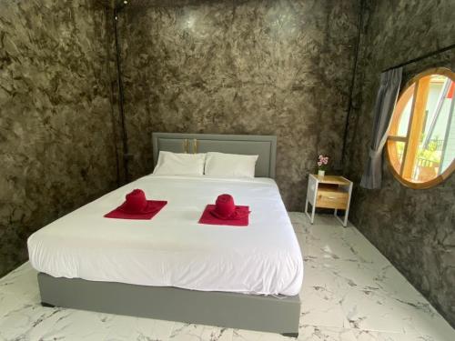 a bedroom with a bed with two red towels on it at Khaosok Foresta Resort in Phanom