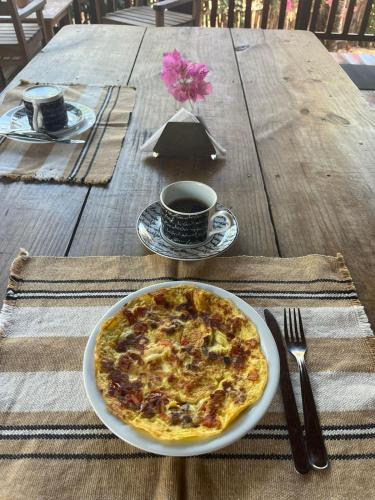 Een bord pizza op tafel met een kop koffie. bij Casa Wayra in Barra Grande