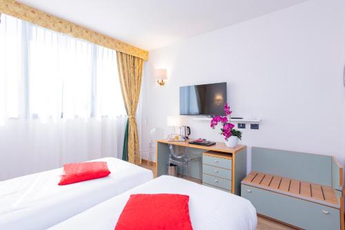 a bedroom with two beds and a desk with a computer at AN Hotel Milano San Donato in San Donato Milanese