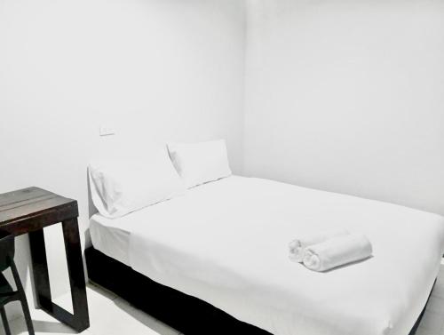 a white bed in a room with a table at xx Mitr inn Khaosan มิตร อินน์ ถนนข้าวสาร in Bangkok