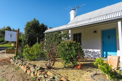 a white house with a blue door and a garden at Blume Cottage 1860 in Stockwell