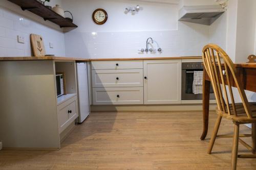 a kitchen with white cabinets and a sink and a table at Blume Cottage 1860 in Stockwell