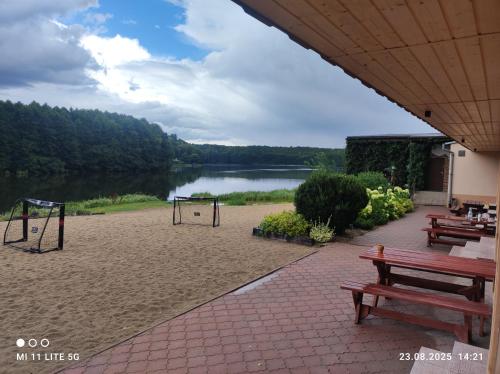 a picnic area with benches and a playground next to a lake at Ośrodek Wypoczynkowy Sosenka in Załom