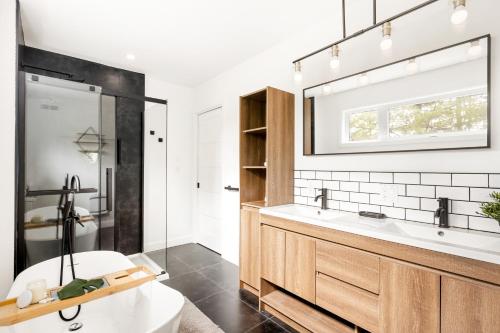 a bathroom with a tub and a sink and a mirror at Le chalet ALTO - Nature & Détente in Saint-Alexis-des-Monts