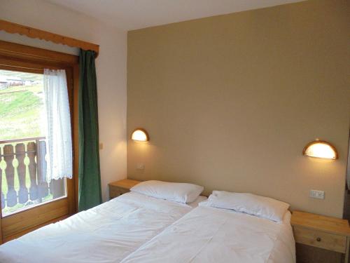 a bedroom with a white bed and a window at Casa Gembre in Livigno