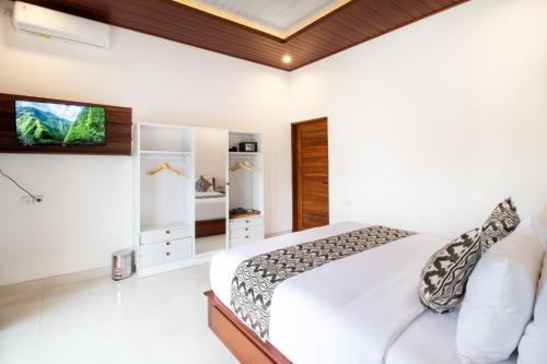 a bedroom with a bed and a tv on a wall at Doa Ubud Villa in Ubud