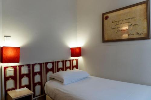a room with a bed with two lamps and a picture on the wall at Hotel Ours Blanc - Victor Hugo in Toulouse