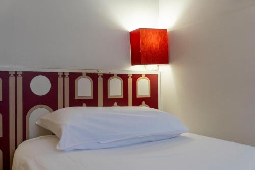 a white bed with a red headboard and a red lamp at Hotel Ours Blanc - Victor Hugo in Toulouse