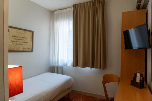 a hotel room with a bed and a television at Hotel Ours Blanc - Victor Hugo in Toulouse