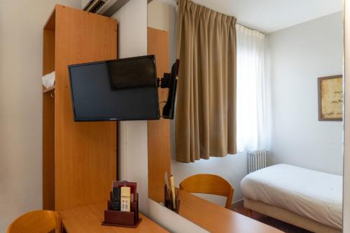 a room with a bed and a tv on a wall at Hotel Ours Blanc - Victor Hugo in Toulouse