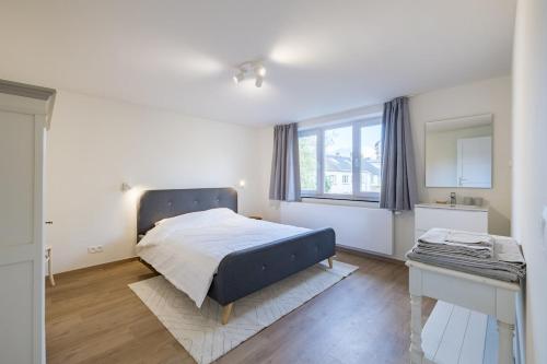 a white bedroom with a bed and a window at Adorable maison 3ch proche de Bruxelles-Tervuren in Tervuren