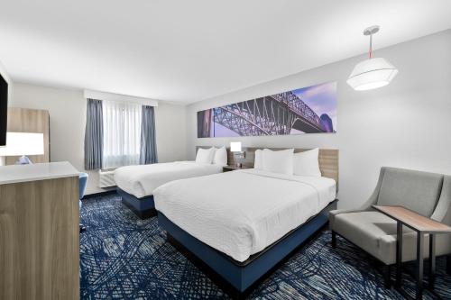 a hotel room with two beds and a chair at Clarion Pointe in Shreveport