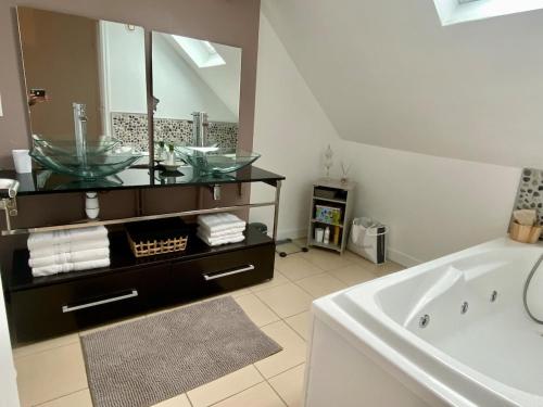 a bathroom with a sink and a tub and a mirror at Maison Onze calme en bord de Rance in Plouër-sur-Rance