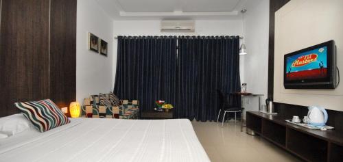 a bedroom with a bed and a tv and a window at The New Marrion in Bhubaneshwar