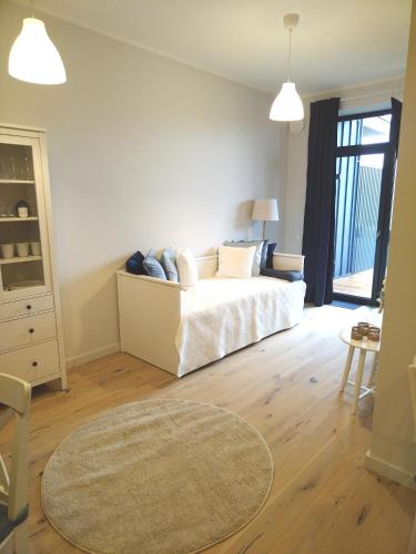 a bedroom with a white bed and a rug at Albatross Apartment Sea in Ķesterciems