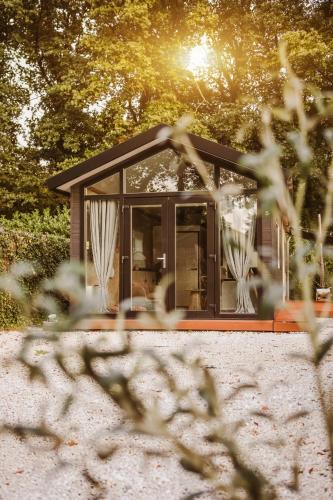 a small house is seen through the trees at Cozy Stay Veluwe met hottub in Putten