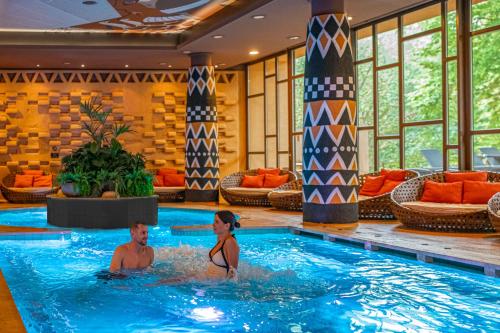 a man and woman sitting in a swimming pool at Bambara Hotel in Felsőtárkány
